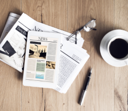 newspaper, glasses, coffee cup and pen on a table