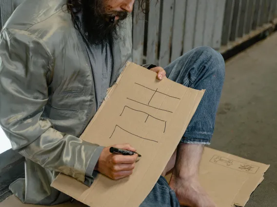 A Homeless man writing HELP sign