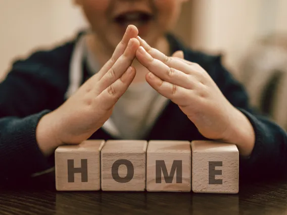 Boy making roof hands under wooden cubes