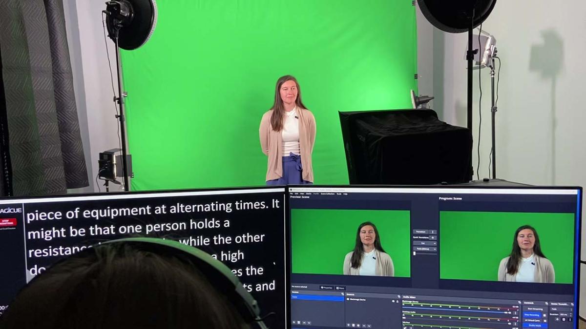 student standing in front of green screen - Tulane SoPA