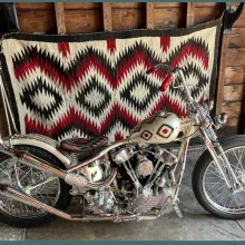 a custom-painted motorcycle is displayed in front of a Navajo textile, both showing the same designs