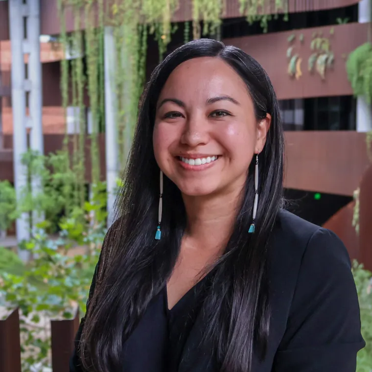 Britnee poses in dangling earrings and a black blouse at the U of A ENR2 building