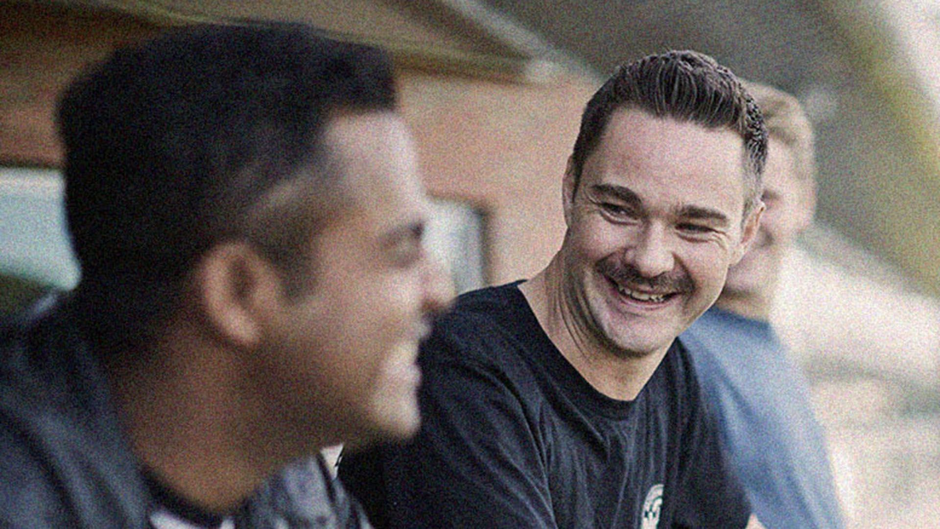 Photo of two smiling men having a conversation.