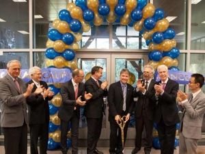 8 people standing in front of blue and gold balloons. One man holds a shovel.