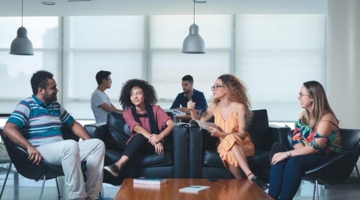 Alunos conversando sentados no sofá da área de convivência da FGV.