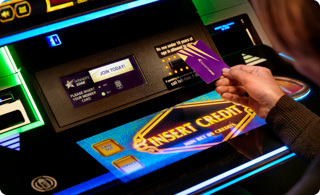 A member hand holding the Winner’s Edge card by a slot machine / casino ATM