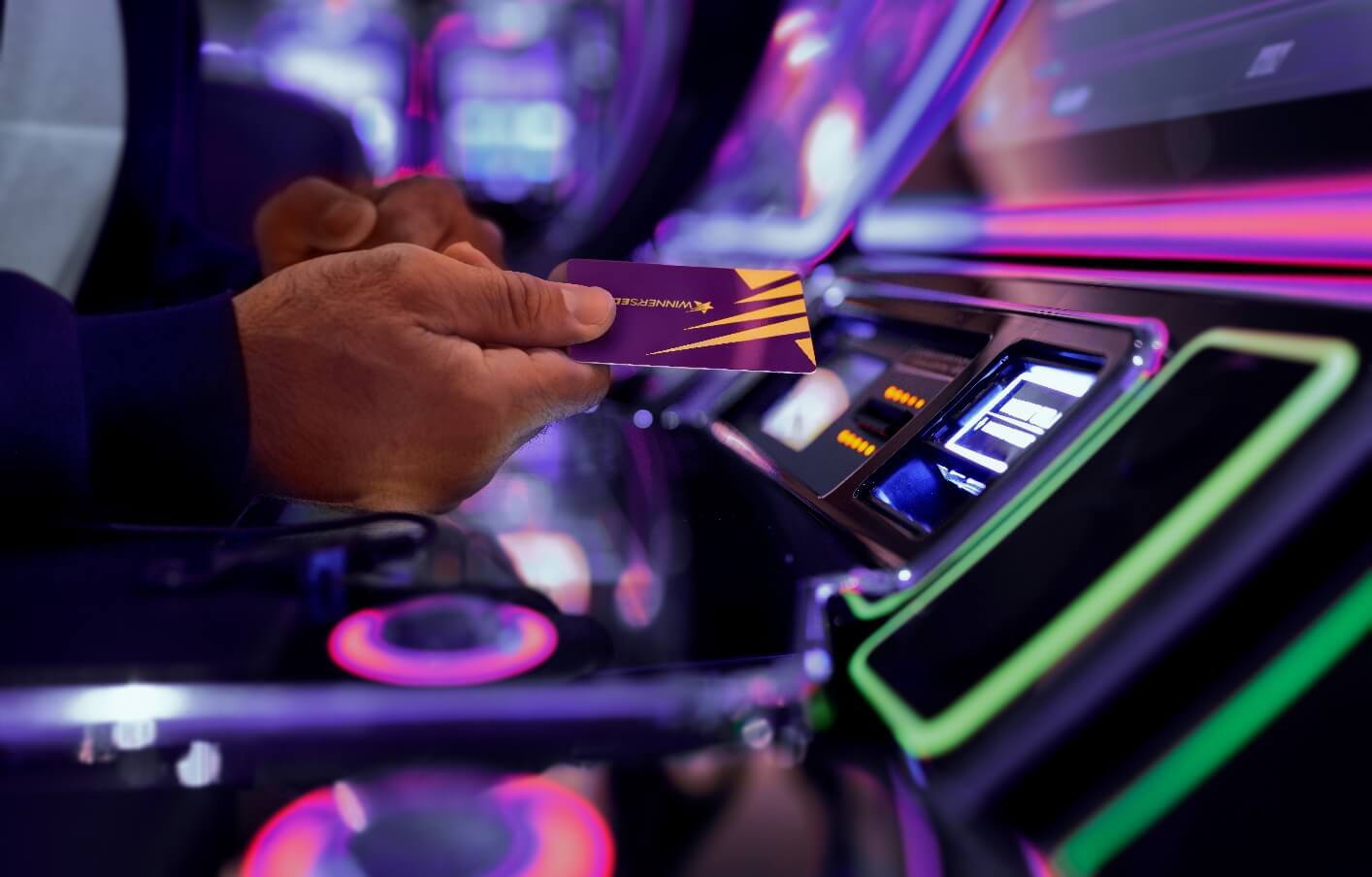 A Winner’s Edge member holding the card by a slot machine