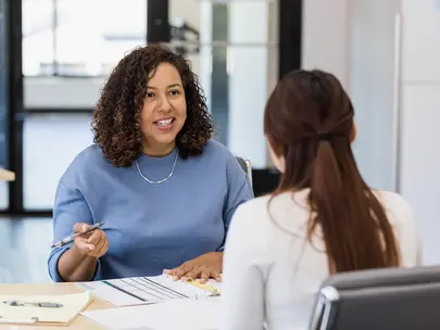 A woman speaks with another woman about assessing their job skills. 