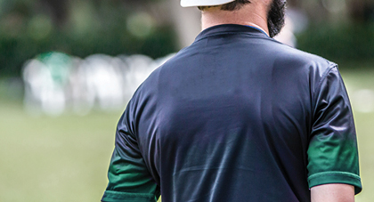 A sports trainer facing the football field and away from the camera.