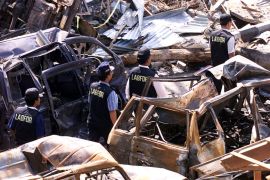 Indonesian police walk past destroyed cars at the site of the October 12, 2002, bomb blasts on Indonesia&#039;s resort island of Bali [File: Beawiharta/Reuters]