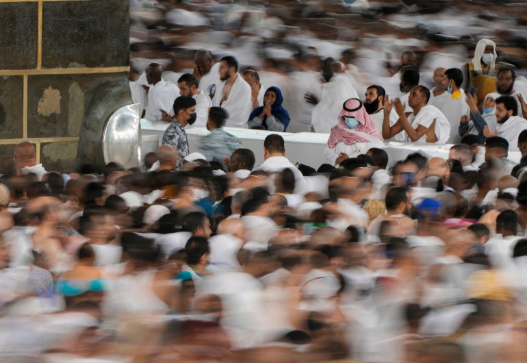 low shutter speed, Muslim pilgrims pray as others circumambulate around the Kaaba