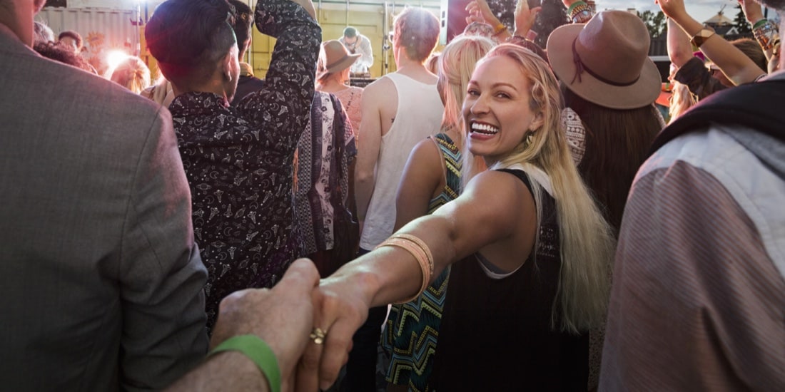 Woman leading through crowd, looking back and smiling