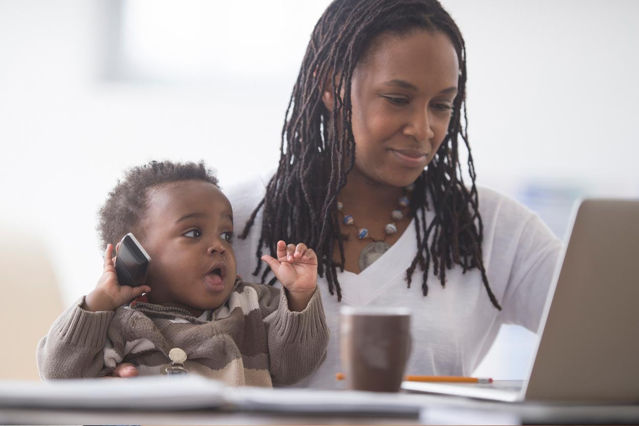 Woman holding her baby looking at a laptop