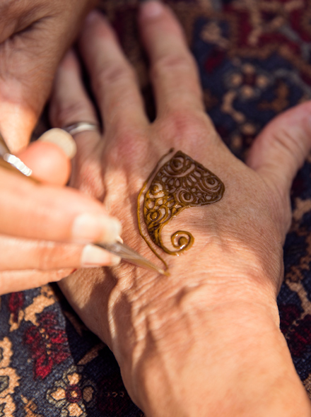 Nahaufnahme einer Hand, auf die ein Hennatattoo gemalt wird.