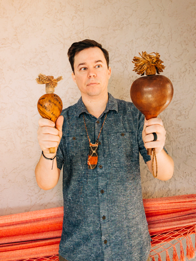 Photo portrait of Frank, holding traditional Indigenous maracas.