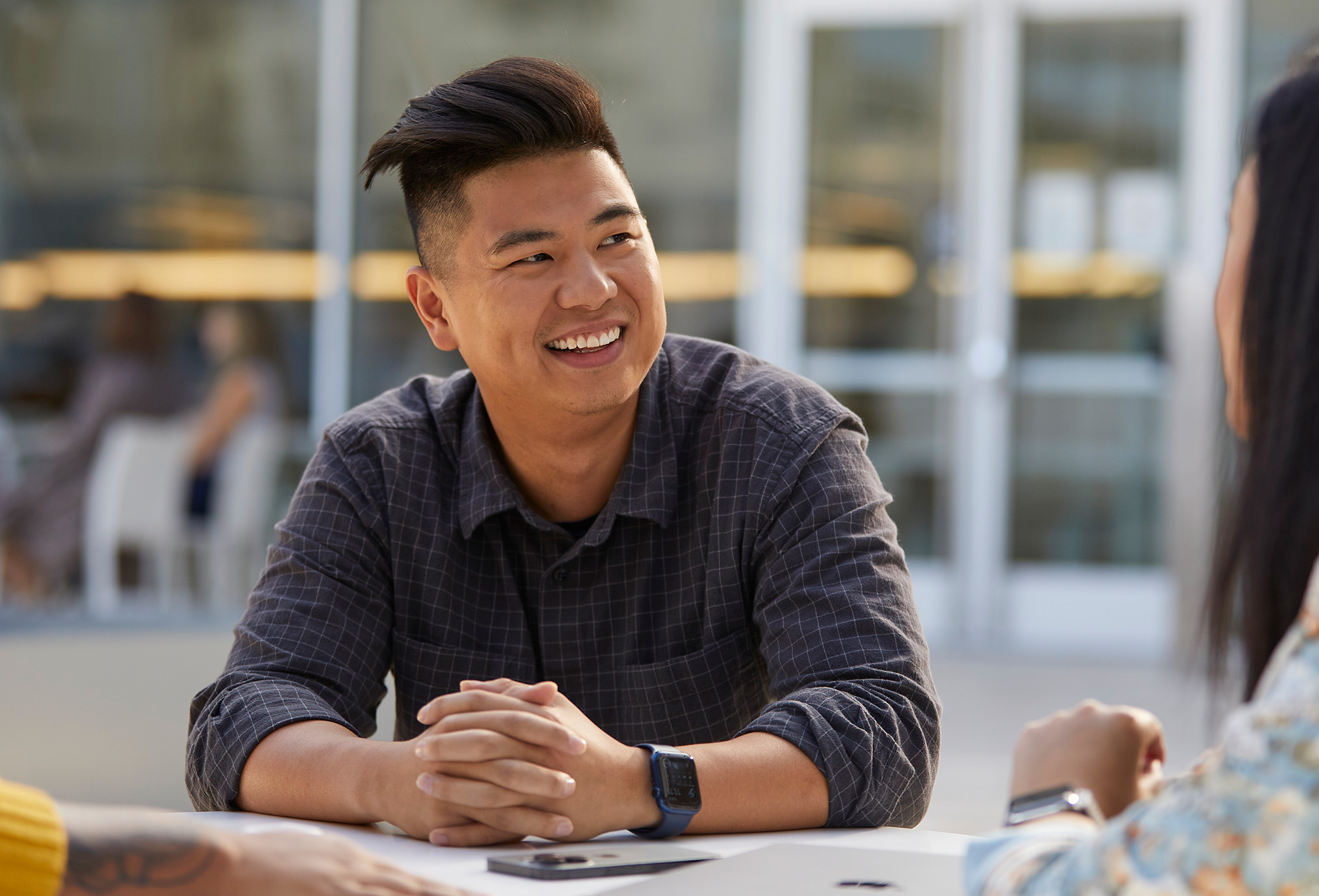 An Apple employee looking to the side and smiling.