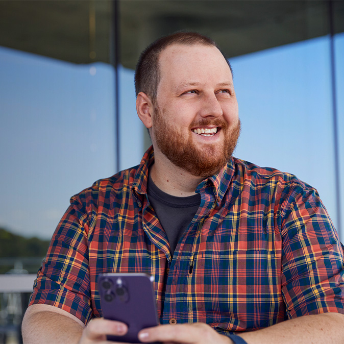 Topher sitting outside an office building, smiling and looking off to the side.