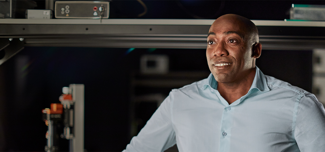 Mike smiling and looking off to the left in an engineering facility, surrounded by equipment.