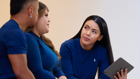 Drie medewerkers van Apple Retail zijn in gesprek. Een van hen houdt een iPad vast.