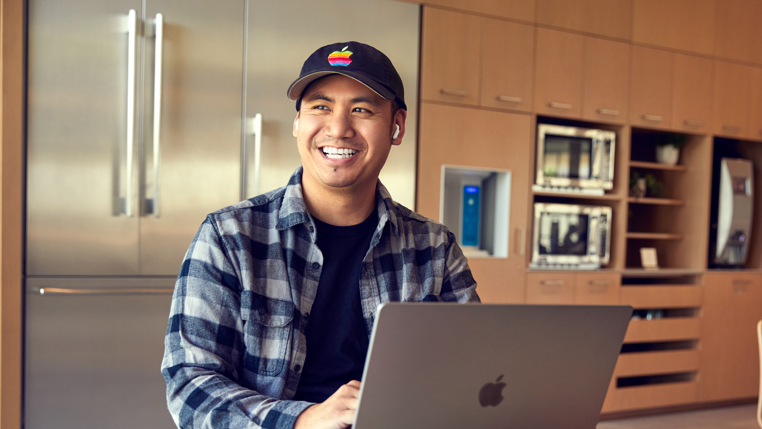一位 Apple 聖地牙哥的員工面帶笑容，正在用他的筆記型電腦工作。