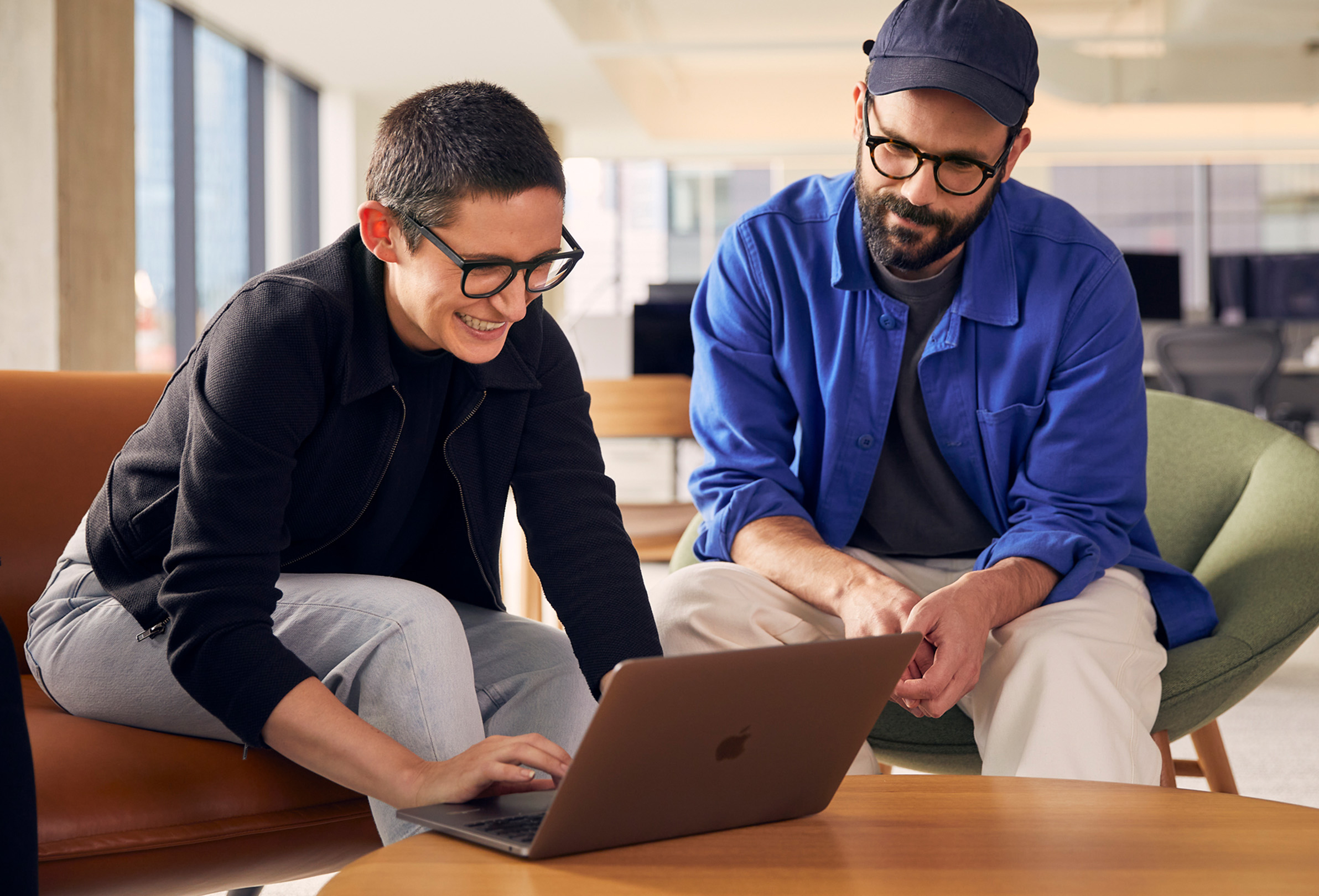 Dois funcionários da Apple usam um MacBook enquanto colaboram.