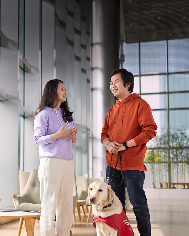 兩名 Apple 員工在明亮的公用空間交談，其中一人拿著服務犬的牽繩。