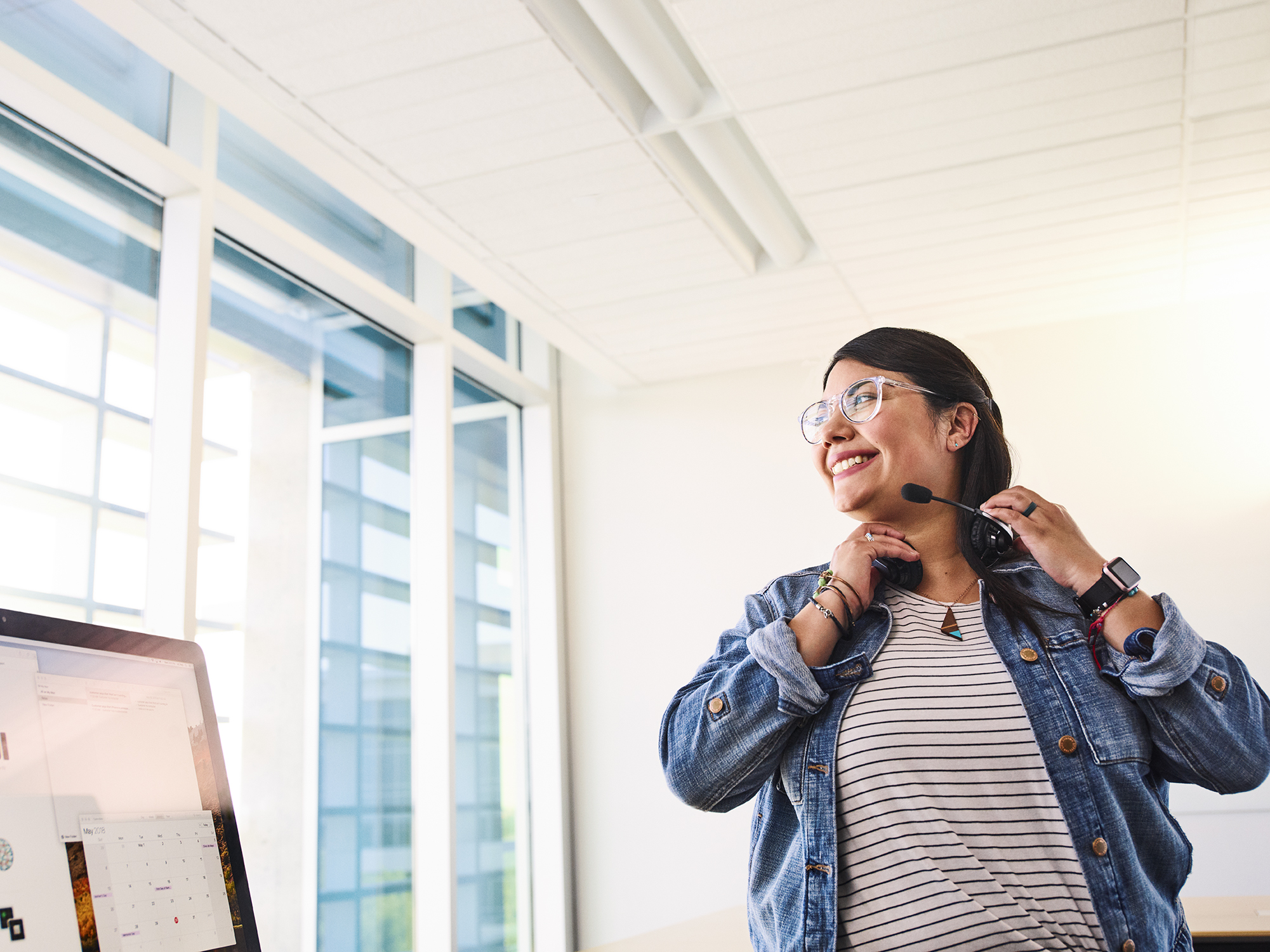 Employée Apple avec un casque d’écoute, assise devant un ordinateur.