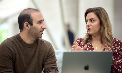 Önünde açık duran bir MacBook olan Desireh, bir çalışma arkadaşıyla konuşuyor.