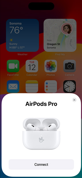 MagSafe Ladecase mit eingesetzten AirPods Pro neben einem iPhone. Eine kleine Kachel auf dem iPhone Homescreen zeigt ein Fenster mit der Taste „Verbinden“, um die AirPods ganz einfach per Fingertipp zu verbinden.