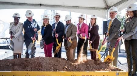 People in hardhats with shovels at groundbreaking event