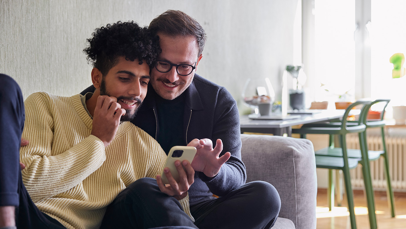 Male couple on sofa reviewing mobile phone