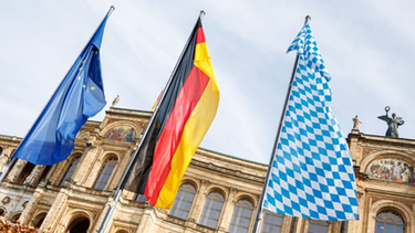 Die europäische, die deutsch und die bayerische Flagge wehen vor dem Maximilianeum, Sitz des Bayerischen Landtags. | Bild: picture alliance / dpa | Matthias Balk