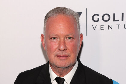 Paul Kemsley standing in front of a step and repeat.