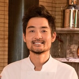 Soo Ahn smiling in his chef uniform inside of a pantry.