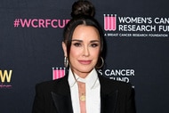 Kyle Richards smiling in front of a step and repeat.