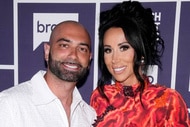 Rachel Fuda and John Fuda pose in front of a step and repeat at the Watch What Happens Live clubhouse in New York City.