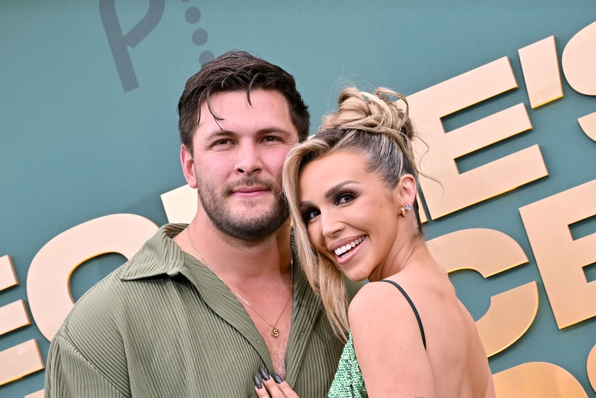 Scheana Shay and Brock Davies hugging and smiling in front of a step and repeat.