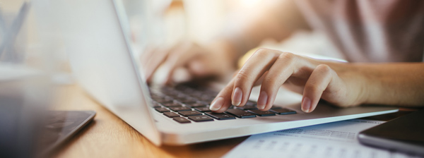 Hände tippen auf einer Laptop-Tastatur