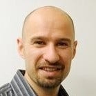 bald man with reddish beard and mustache gray shirt with white strips 