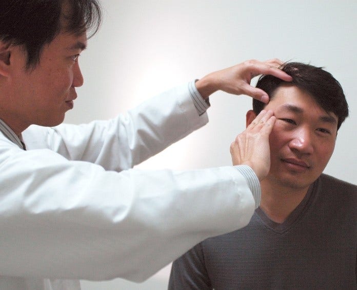 doctor examining man's skin in exam room