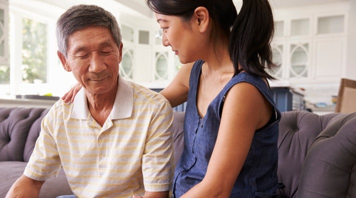 adult daughter talking to and comforting her father