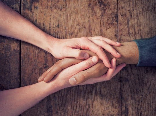 close up of a pair of female hands holding a male hand 