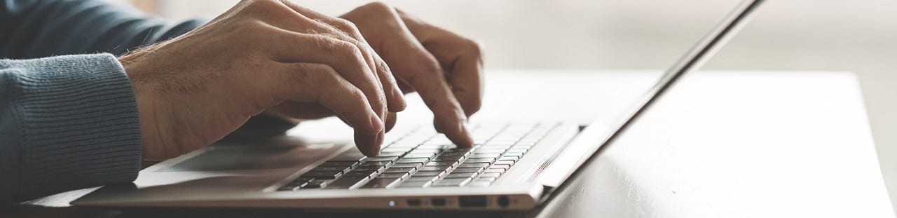 close up of hands typing on laptop keyboard