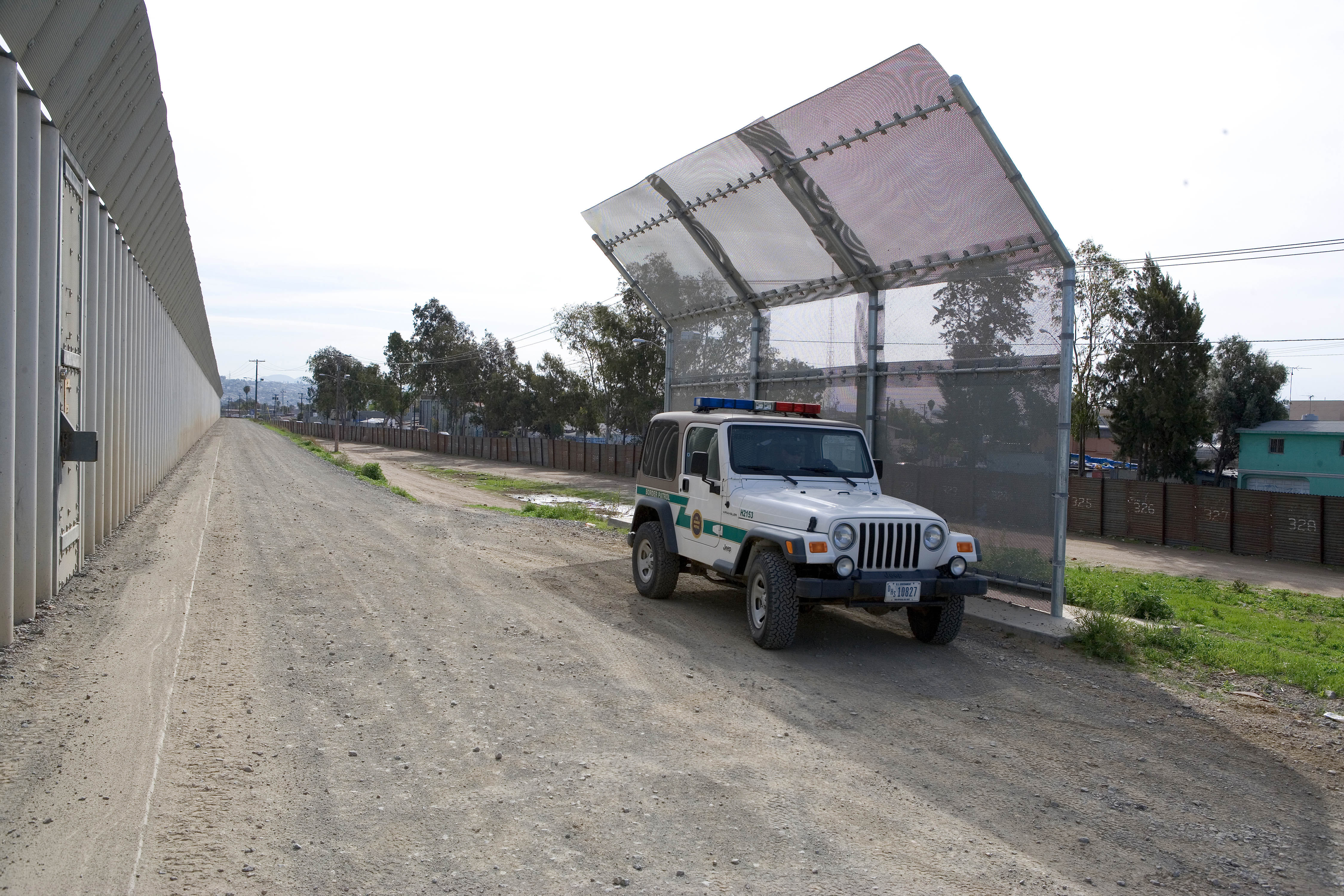 Border Patrol agents sit next to an improvised fence to protect them against rocks that are thrown from the Mexican side of the border.