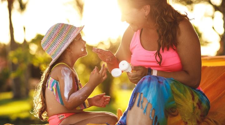 Una mamá poniéndole protector solar a su hija