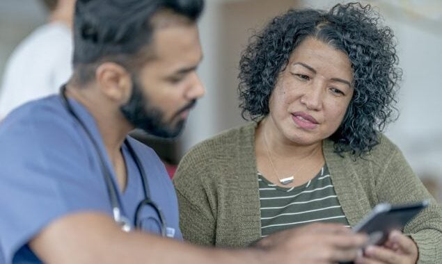 Médico revisando resultados de las pruebas con una paciente de mediana edad.