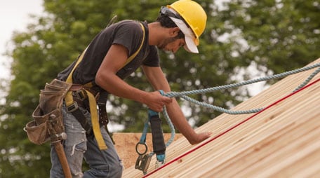 Trabajador en un techo que lleva cinturón de seguridad