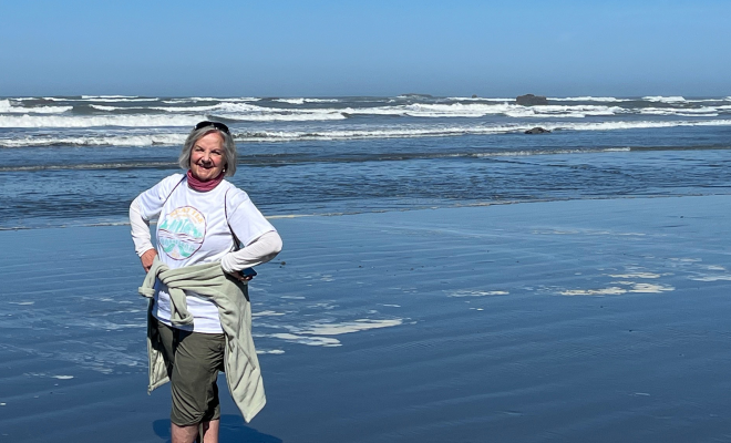 Julie Carel smiling on the beach in front of the ocean