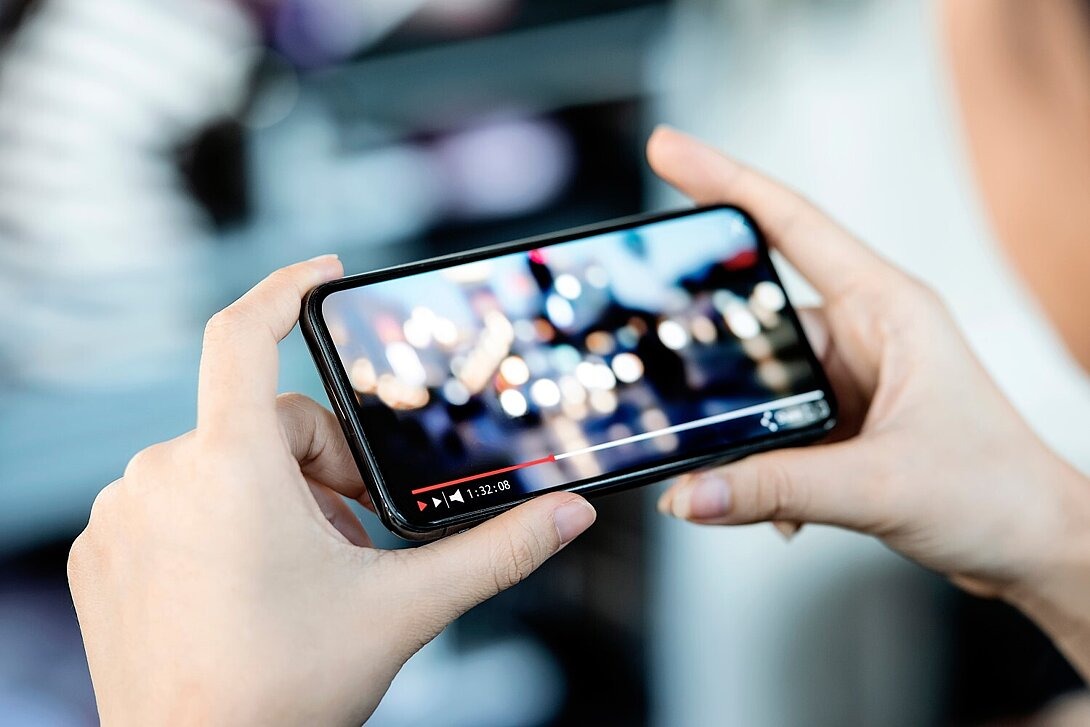 Frau schaut Video auf einem Handy. 