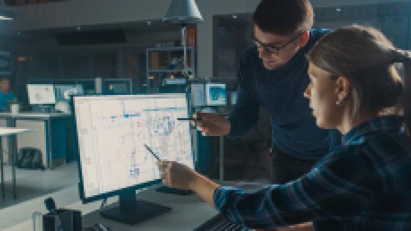 A man and a woman discussing data on a computer screen